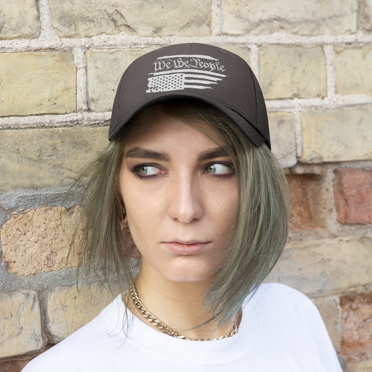 We The People On Distressed American Flag Twill Cap worn by a model against a brick wall.