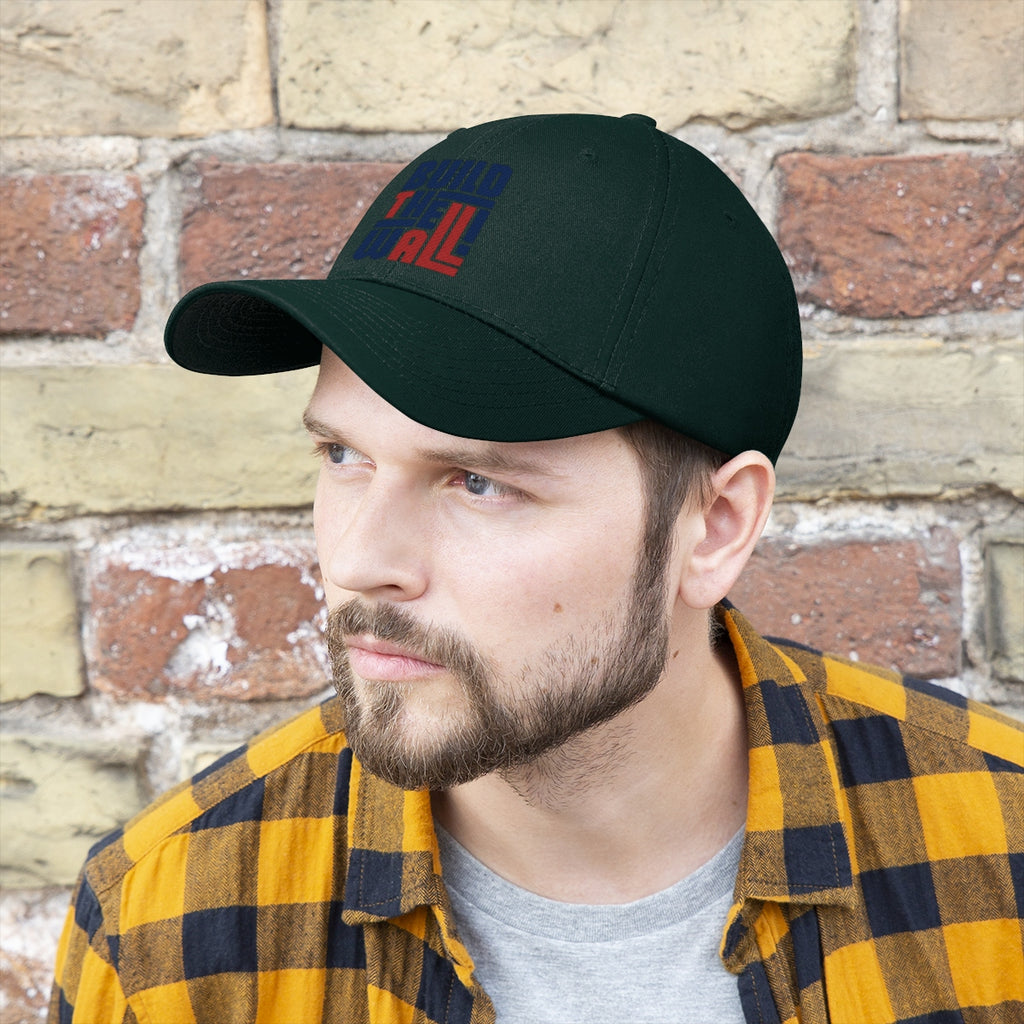 Build The Wall Twill Cap Classic Statement Wear Cap worn by a man against a brick background.
