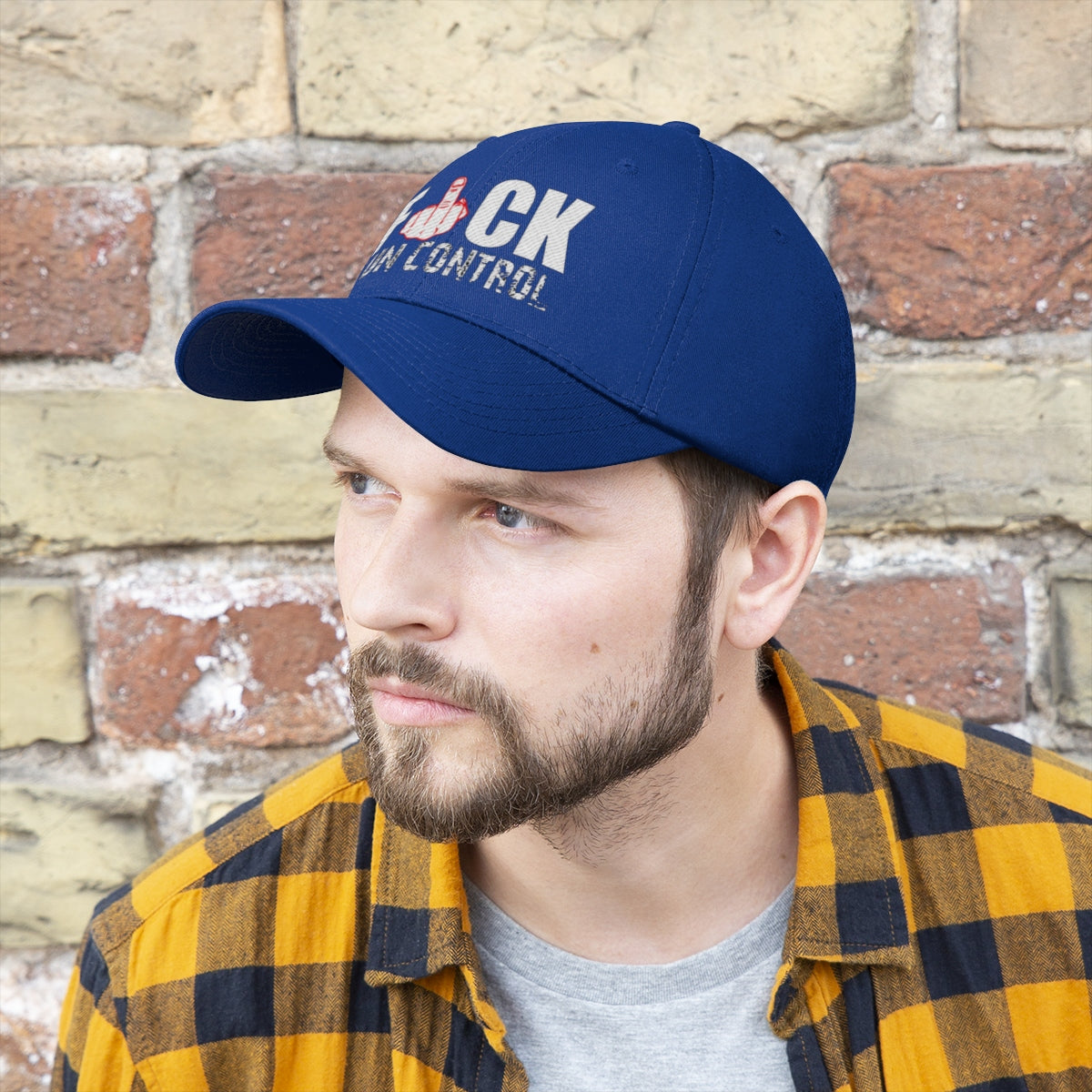 Fuck Gun Control Red Finger Twill Baseball Cap worn by a man against a brick wall.