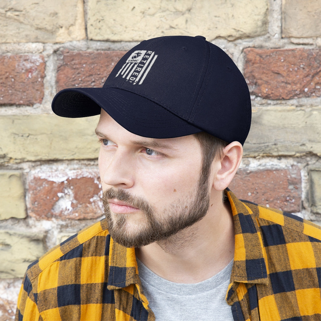 USMC Retired On Distressed American Flag Twill Cap worn by a man with a beard and plaid shirt against a brick wall.