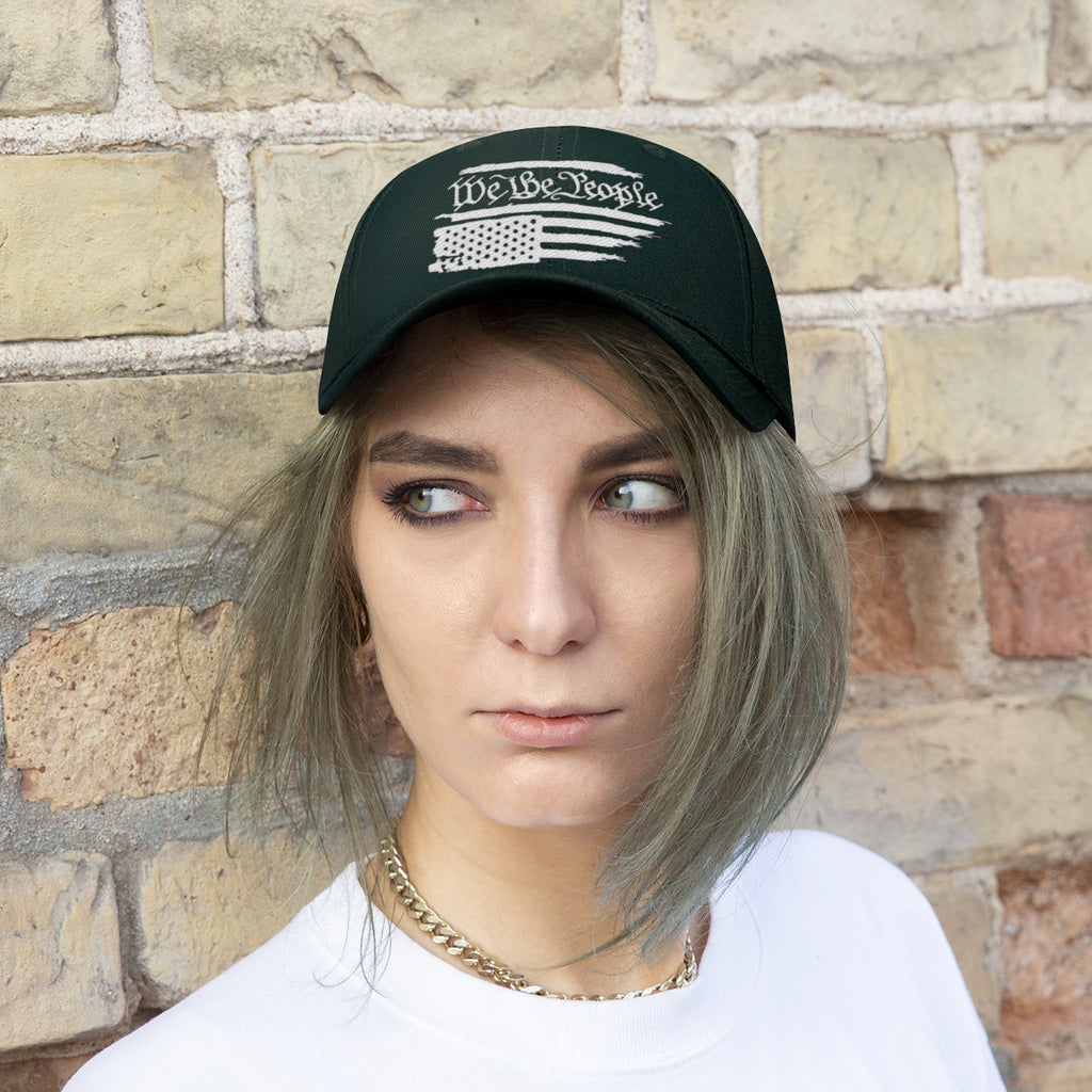 We The People On Distressed American Flag Twill Cap worn by a young woman against a brick wall background.