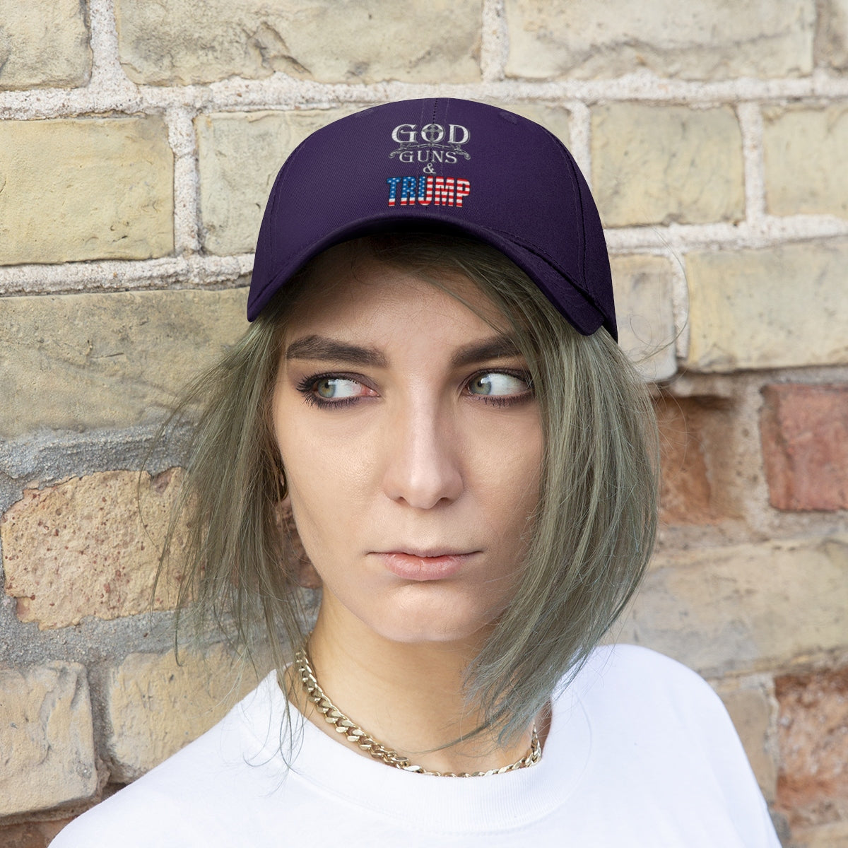 God Guns And Twill Cap Trump Patriotic Statement Hat worn by a young adult against a brick wall background.