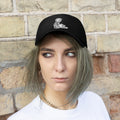 Trump USA Pride Embroidered Twill Cap on a model against a brick wall, showcasing patriotic fashion.