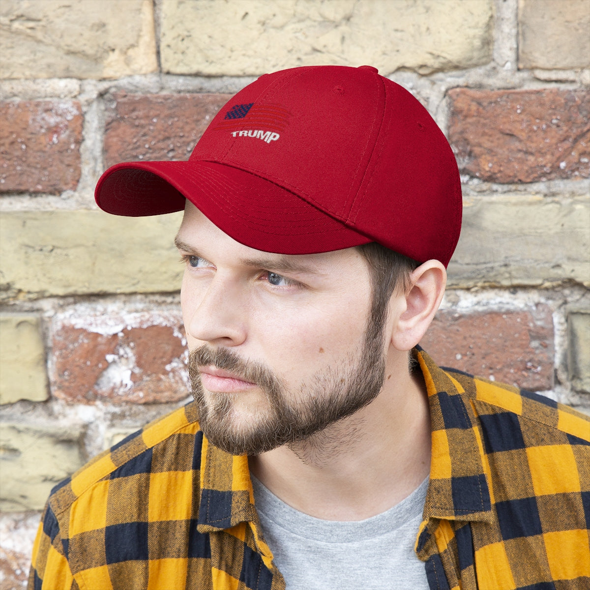American Flag Twill Cap Trump Bold Supporter Cap worn by a man with a beard and checkered shirt, against a brick wall.
