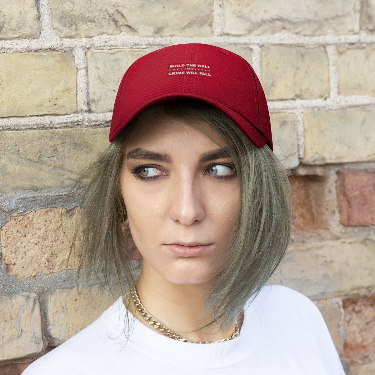 Build The Wall And Crime Will Fall Twill Cap worn by a young woman with short hair, set against a brick wall.