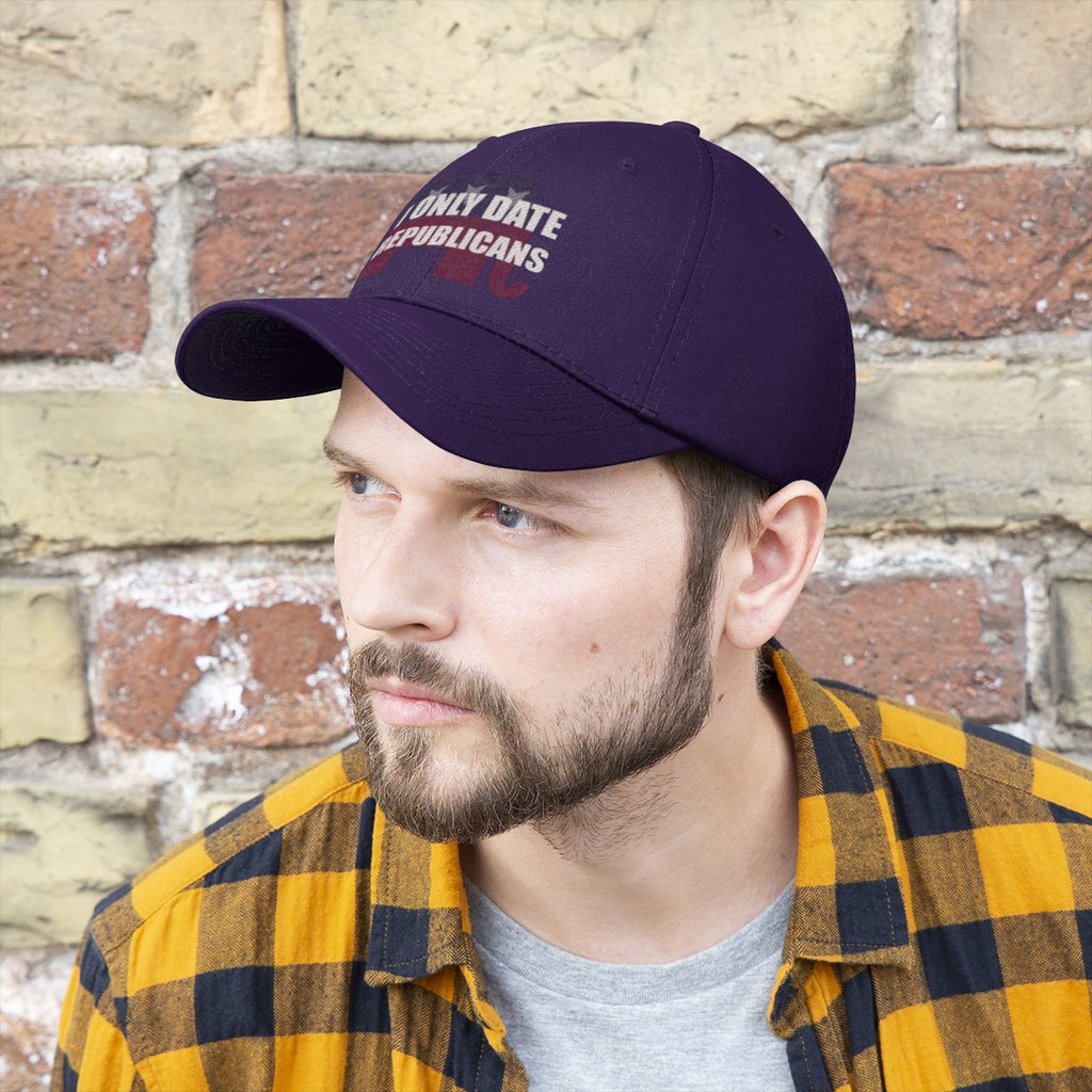I Only Date Republicans Twill Cap displayed on a man wearing a plaid shirt against a brick wall.