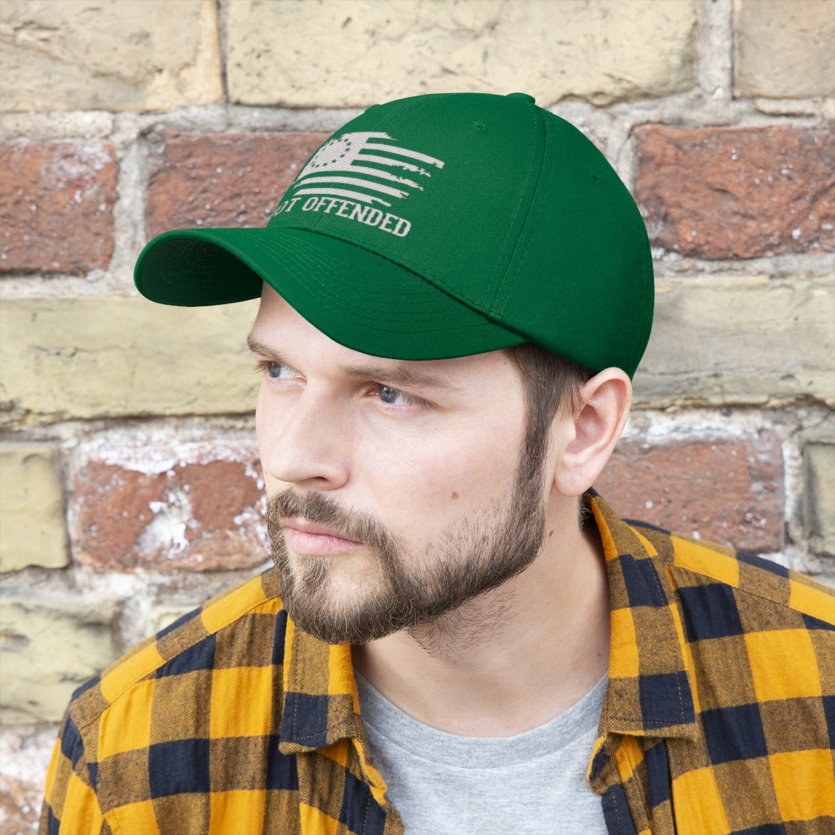 Embroidered Not Offended Adjustable Twill Cap worn by man against a brick wall, showcasing a bold statement design.