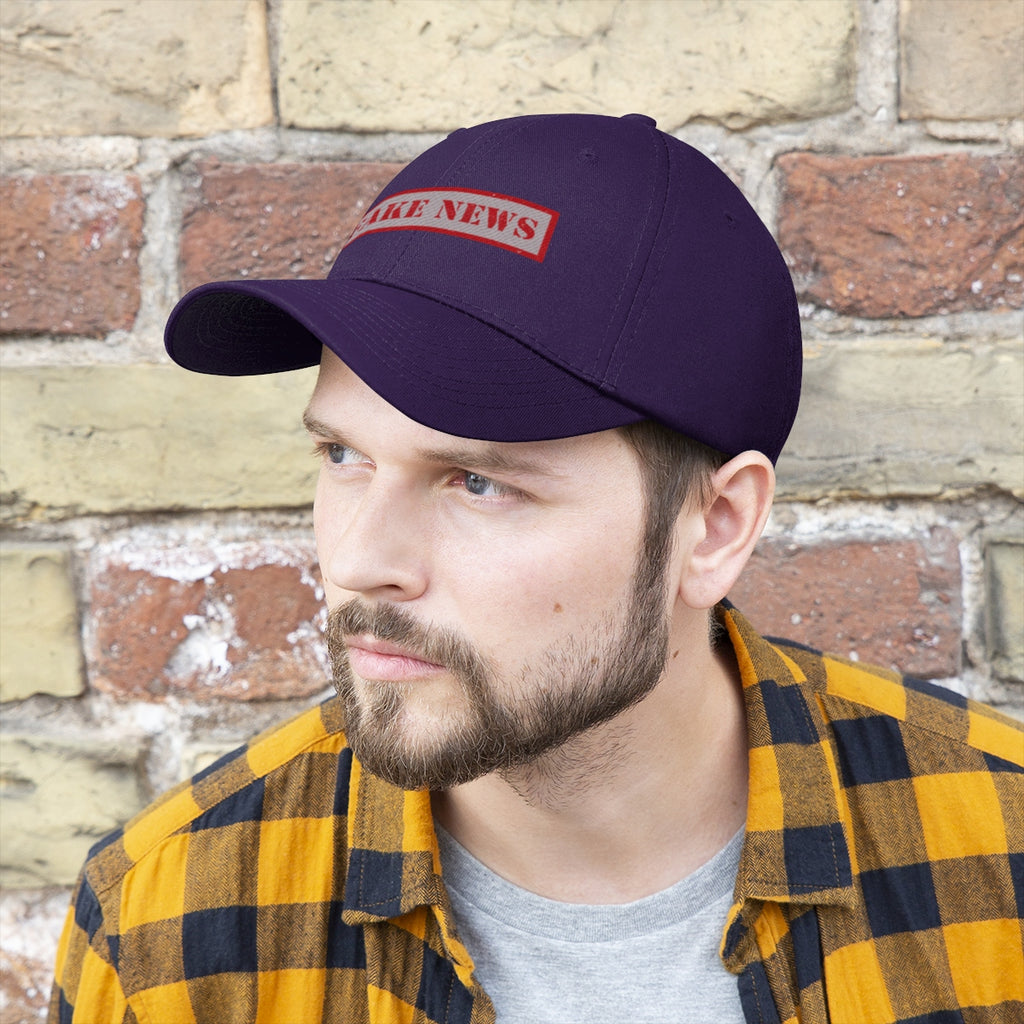 Fake News Twill Cap Bold Humor Casual Wear Hat on a man against a stone wall background.