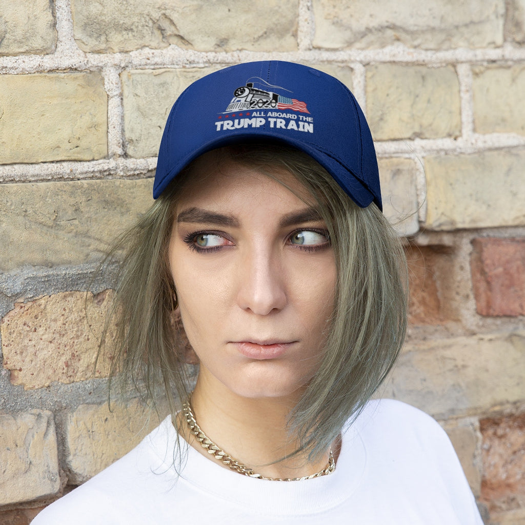 Person wearing All Aboard The Trump Train 2020 Twill Cap against a brick wall, showcasing political pride.