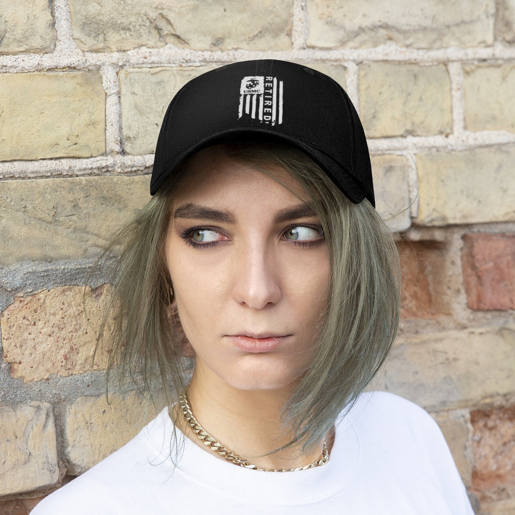 USMC Retired On Distressed American Flag Twill Cap worn by model against a brick wall backdrop.
