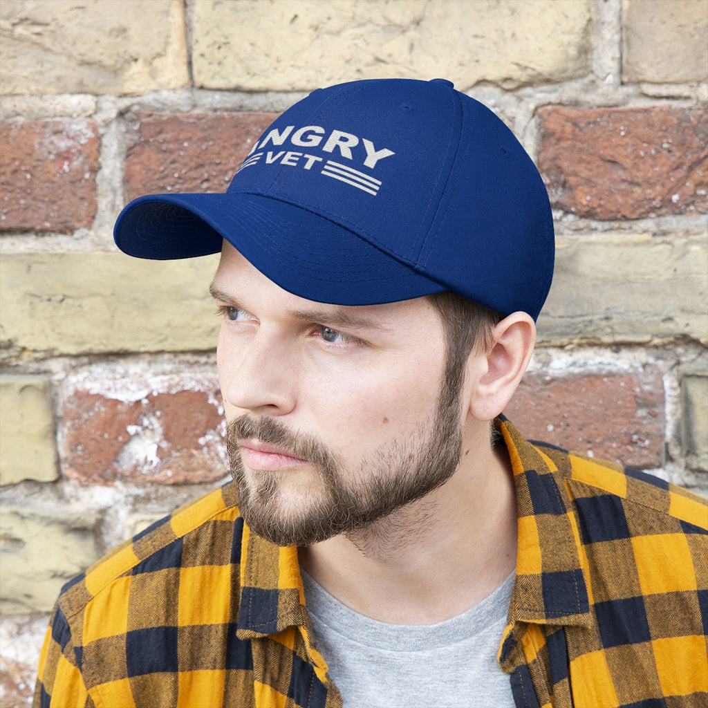 Angry Vet Twill Cap Veteran Pride Graphic Hat worn by a man with a beard, set against a brick wall.