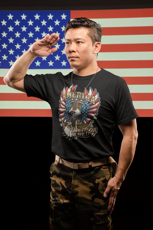 Man saluting in front of American flag, wearing America Love It Or Leave It Graphic Design t-shirt and camo pants.