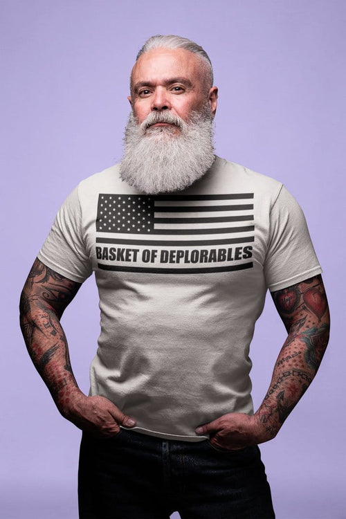 Man wearing Basket Of Deplorables On American Flag graphic tee with tattoos, showcasing bold counter-cultural design on purple background.