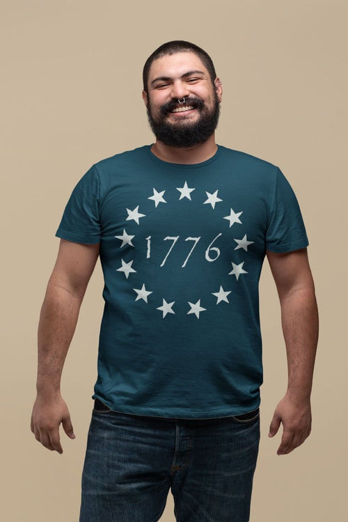 Man wearing Betsy Ross 1776 Stars Vintage American Flag Tee Shirt, smiling against a neutral background.