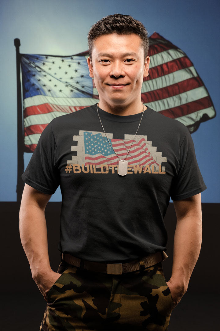 Man wearing a Build The Wall Bold Statement Design shirt in front of American flags.