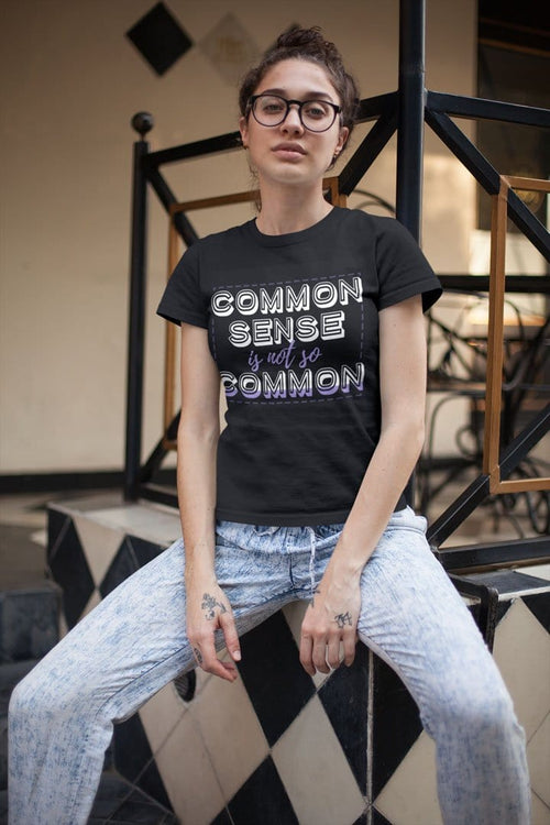 Woman wearing "Common Sense Iss Not So Common" t-shirt, bold intellectual message on casual black tee.