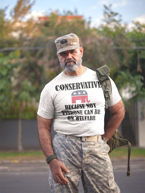 Man wearing camo and t-shirt with text: 'Conservative Because Not Everyone Can Be On Welfare' standing outdoors.