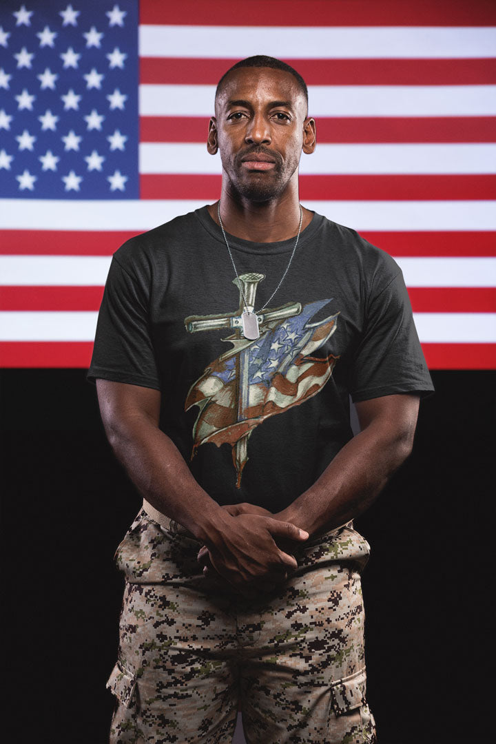Model wearing Dagger and American Flag Graphic Tee with a military-inspired design, standing in front of an American flag backdrop.