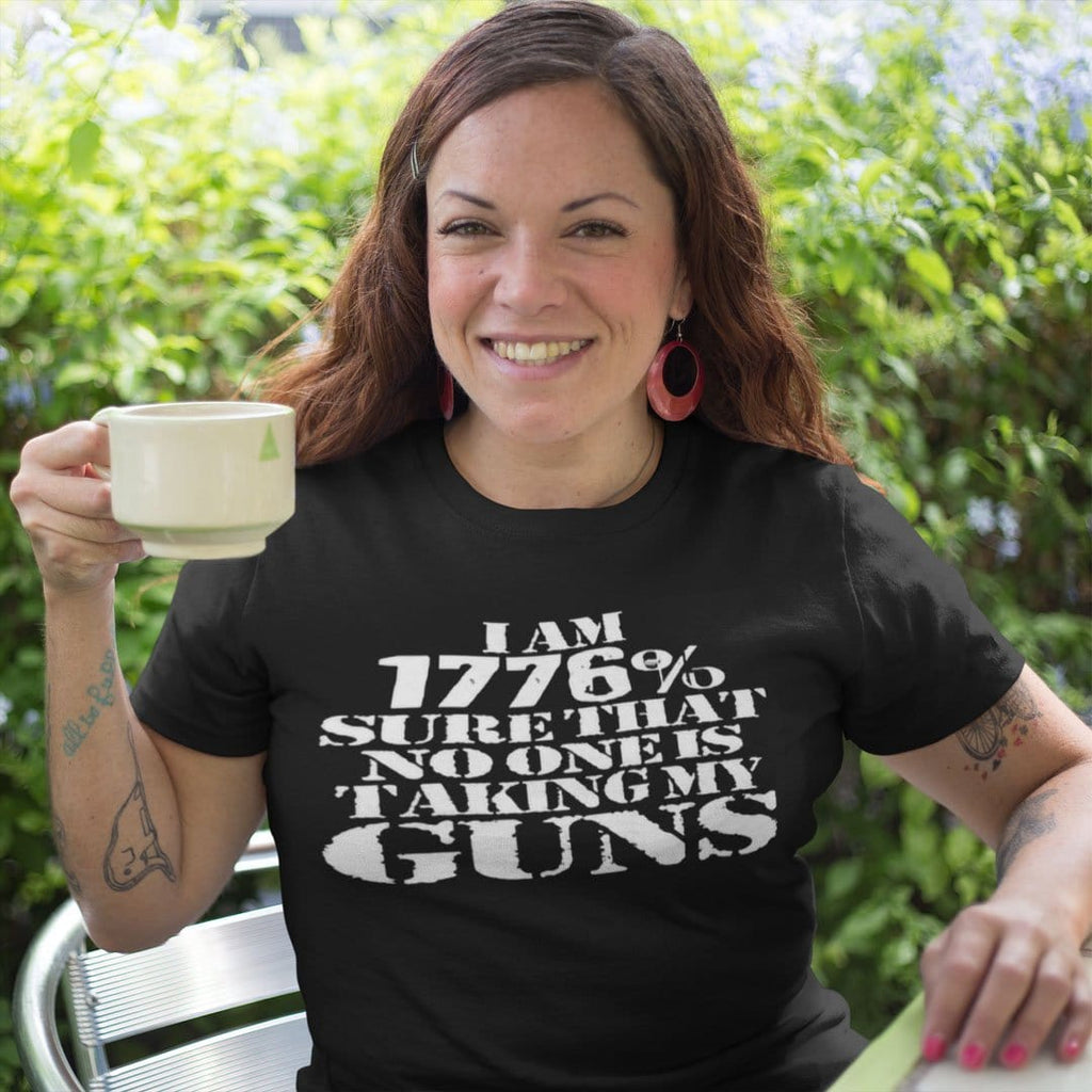 Woman wearing 'I Am 1776 Sure That No One Is Taking My Guns' shirt, holding a cup, smiling outdoors
