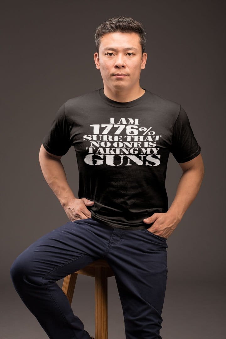 Man wearing "I Am 1776 Sure That No One Is Taking My Guns" t-shirt, sitting on a stool.