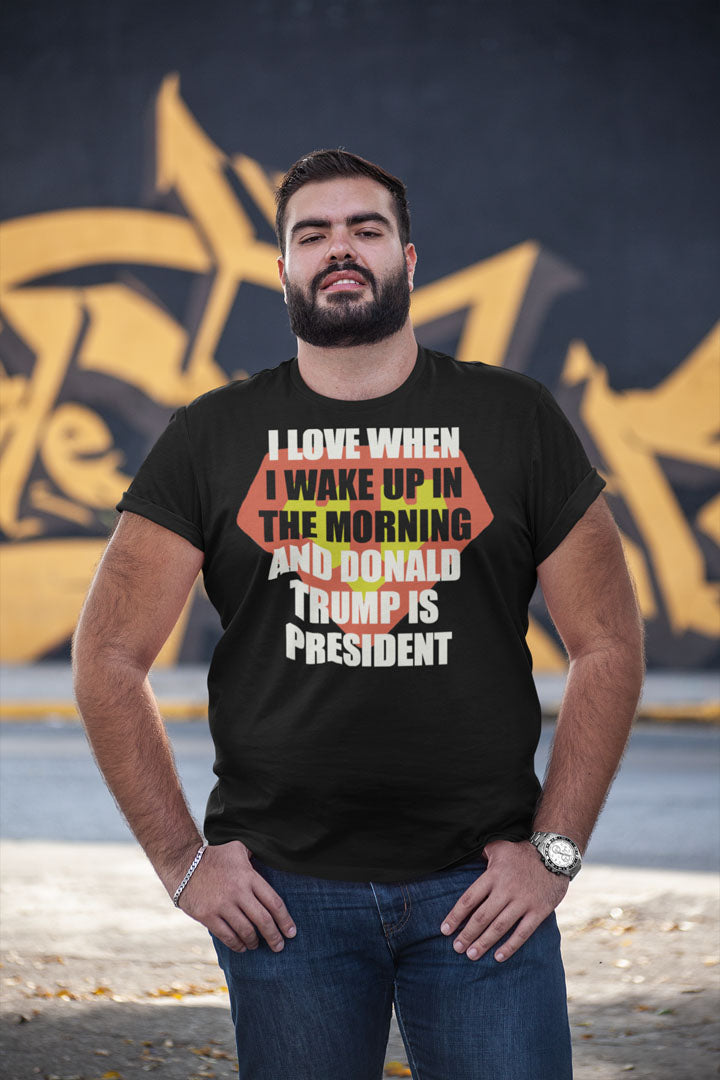 Man wearing 'Love Waking Up When Donald Trump Is President' t-shirt, standing outdoors.