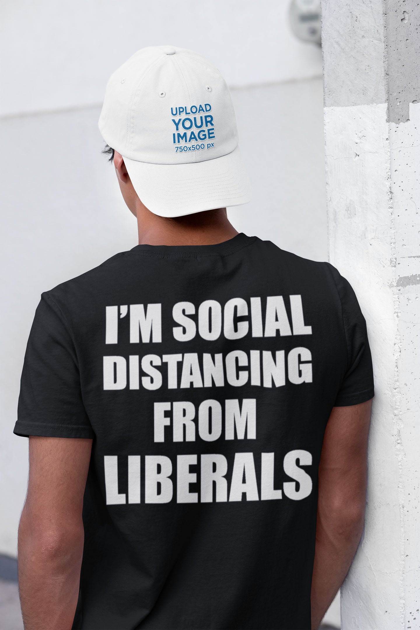 Person wearing 'I'm Social Distancing From Liberals Blk On Back' shirt standing near a wall, showcasing bold political apparel.