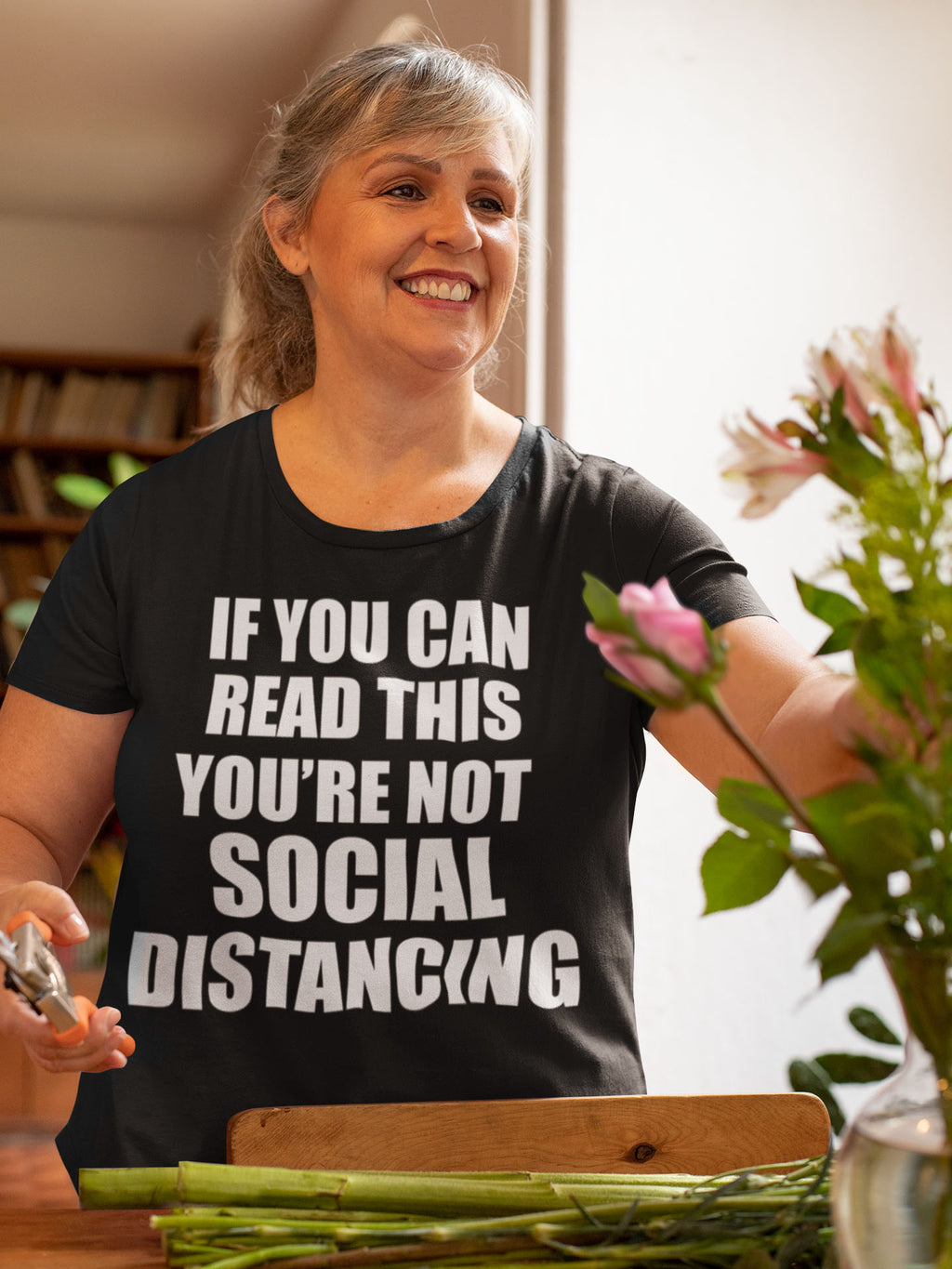 Woman wearing 'If You Can Read This Not Social Distancing Statement Tee' while arranging flowers.