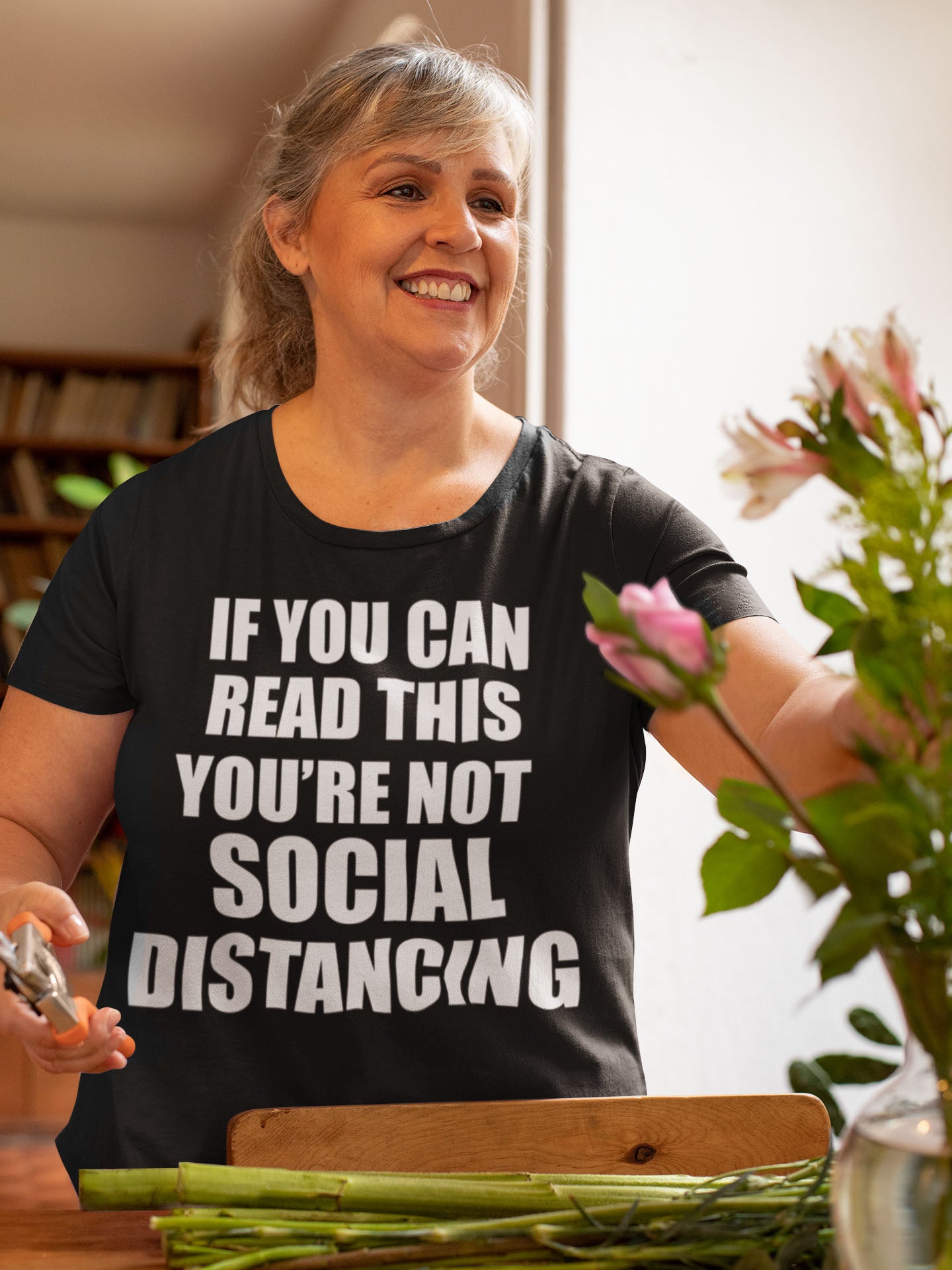 Woman wearing 'If You Can Read This Not Social Distancing Statement Tee' while arranging flowers.