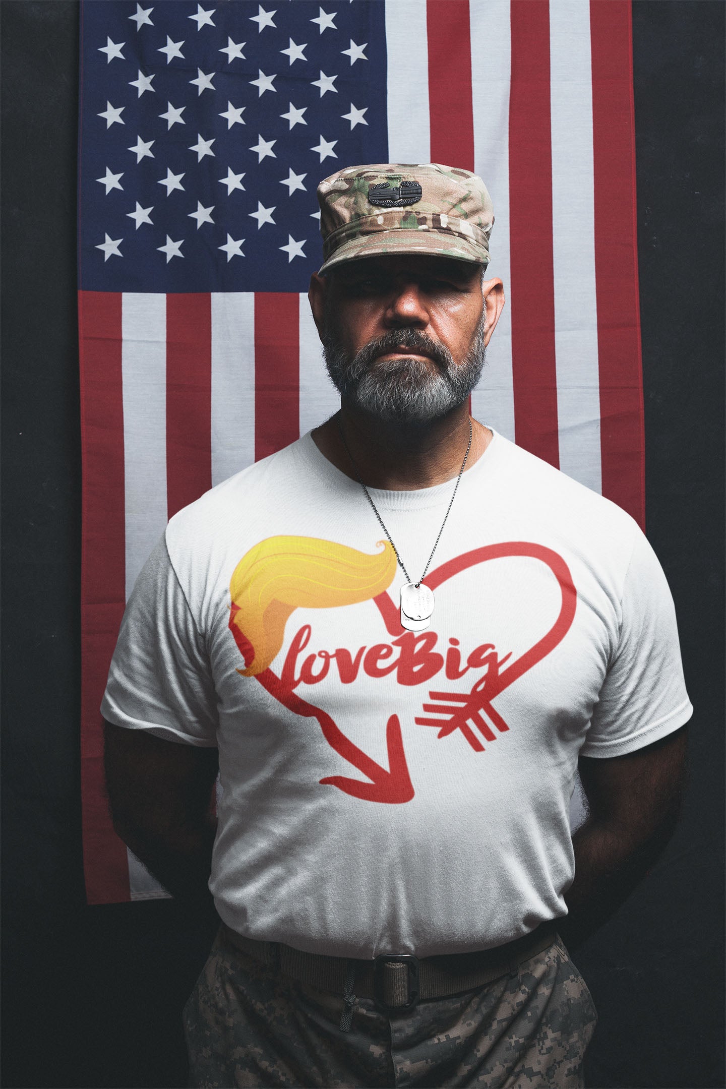 Man wearing Love Big with Trump Hair Graphic Tee standing in front of an American flag.