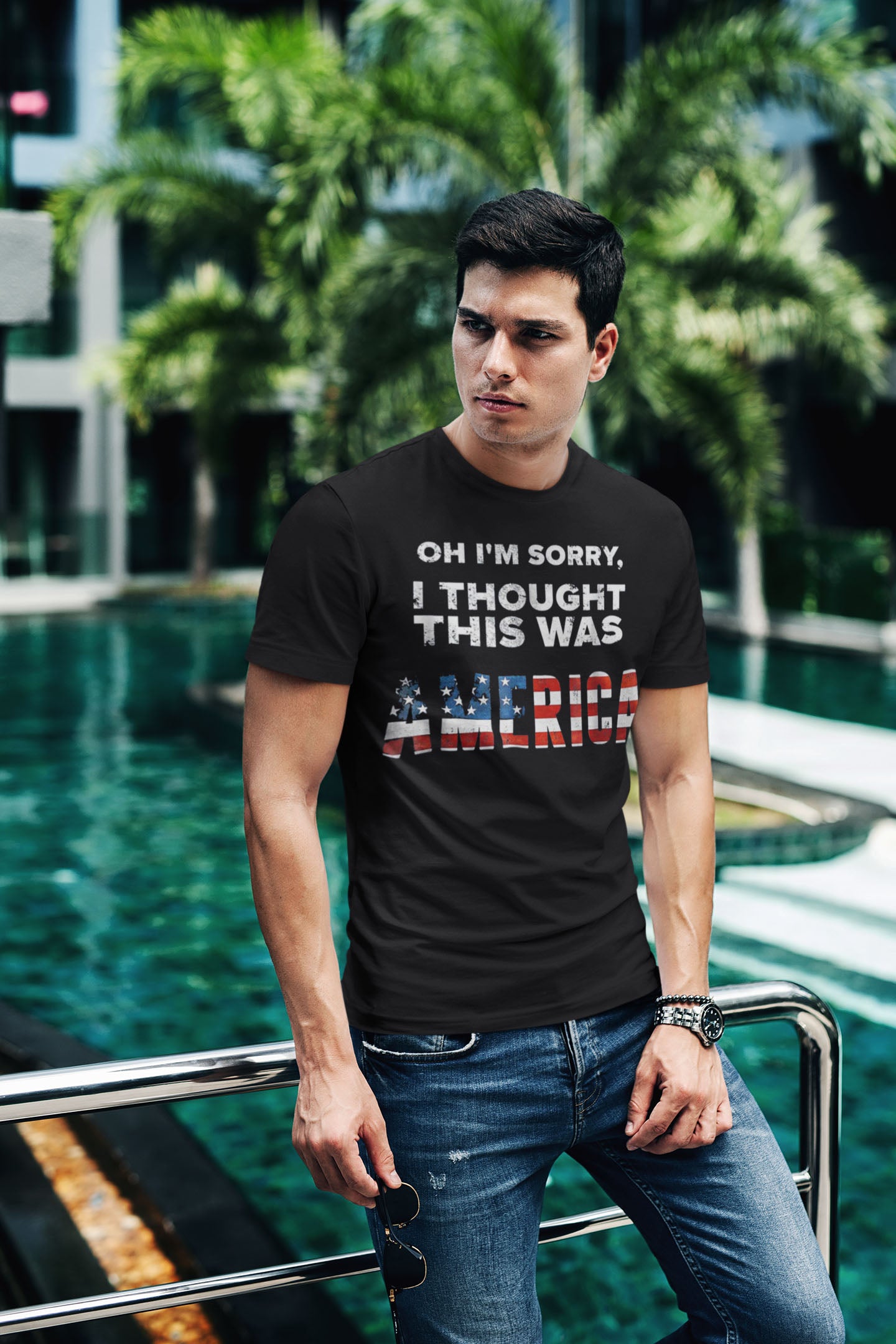 Man wearing 'Oh I'm Sorry I Thought This Was America' t-shirt by a pool.