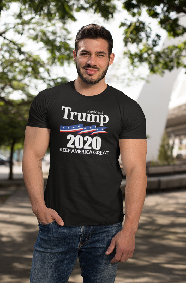 Man wearing black t-shirt with 'President Trump 2020 Keep America Great' slogan outdoors.