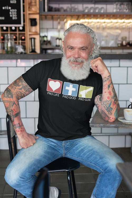 Man wearing a Bold Three-Phrase Graphic Shirt sitting in a cafe, showcasing statement-driven apparel with high-contrast typography.