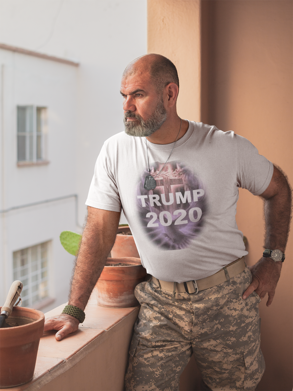 Trump 2020 Cross & Dove Faith Shirt worn by a bearded man in military pants, standing by a window.