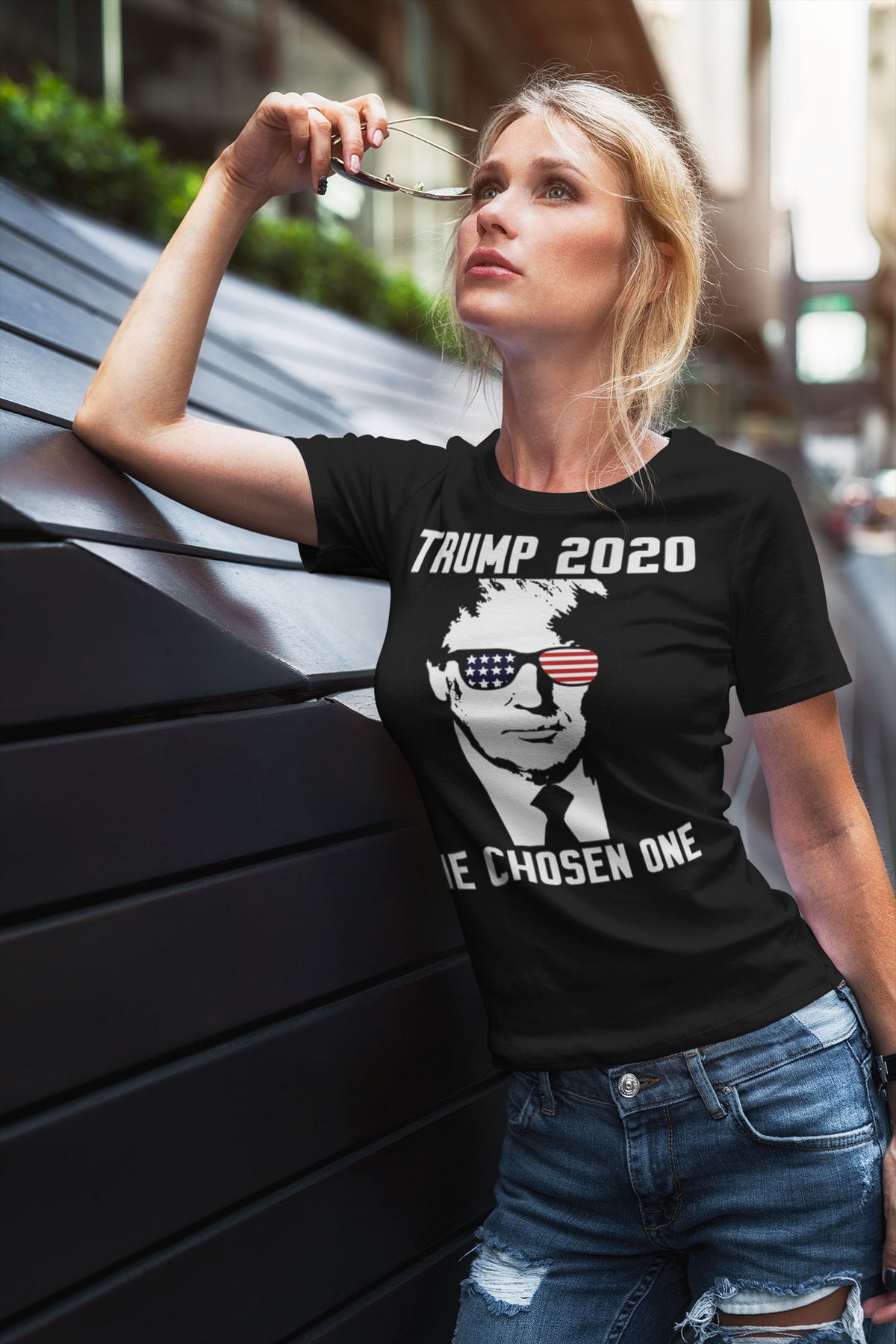 Woman wearing a Trump 2020 The Chosen One USA Shirt posing against a modern backdrop.