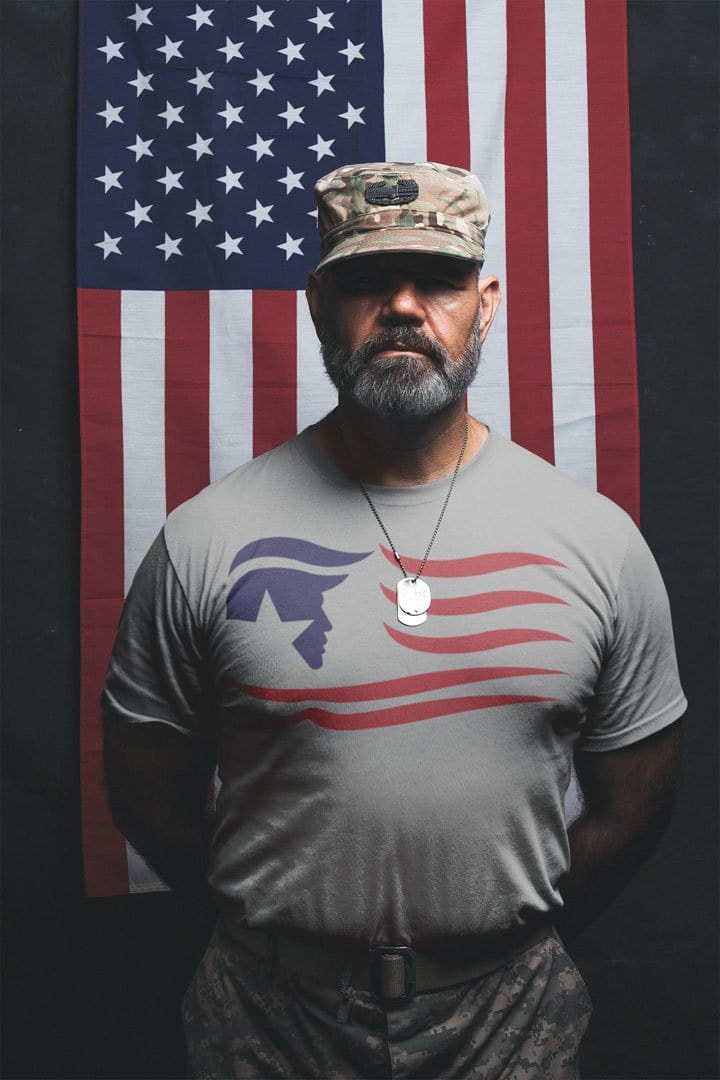 Man wearing Trump Silhouette As American Flag t-shirt stands with American flag backdrop.
