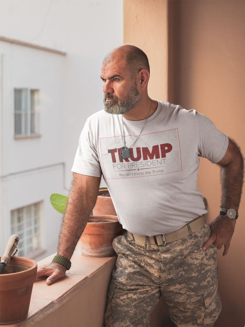 Man wearing Trump For President You Can't Trump The Trump t-shirt on a balcony, showcasing political apparel.