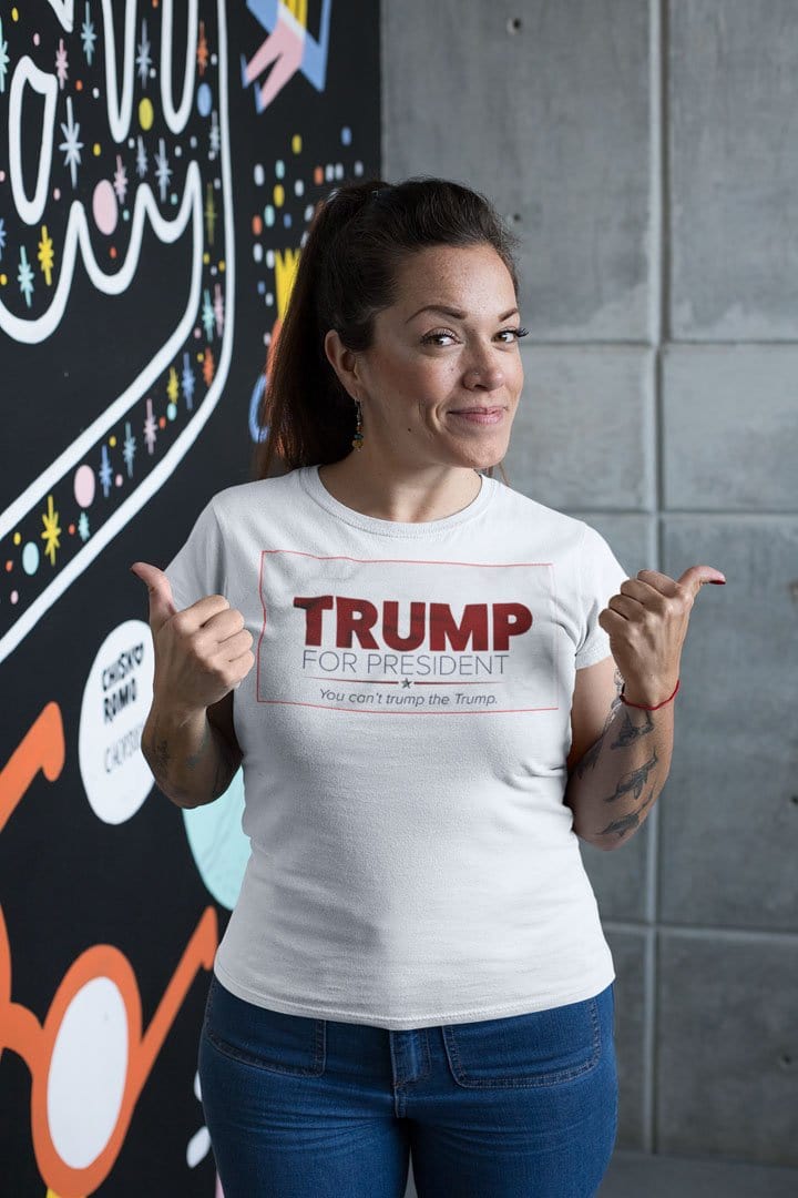 Woman wearing Trump For President You Can't Trump The Trump shirt, smiling and pointing thumbs up, political apparel style.
