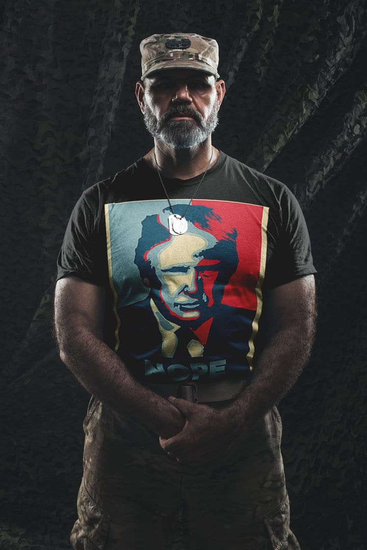 Man wearing Nope Trump Bold Political Statement Graphic Tee Shirt in camouflage setting