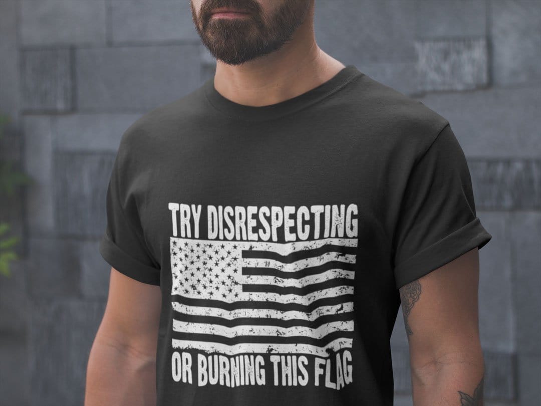 Man wearing "Try Disrespecting Or Burning This Flag" graphic t-shirt, showcasing patriotic apparel in black.