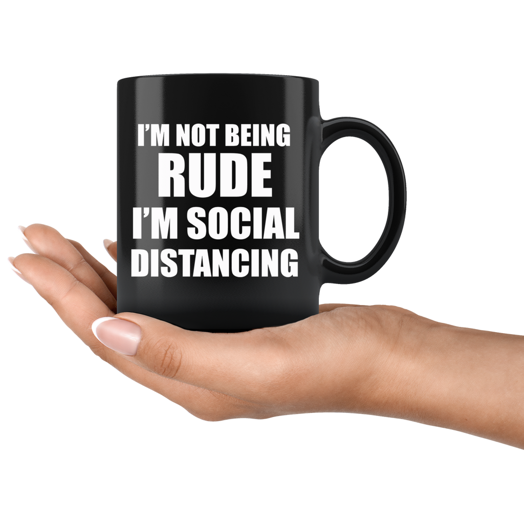 Black mug with bold text "I'm Not Being Rude I'm Social Distancing" held in a hand, showcasing humorous pandemic era statement.