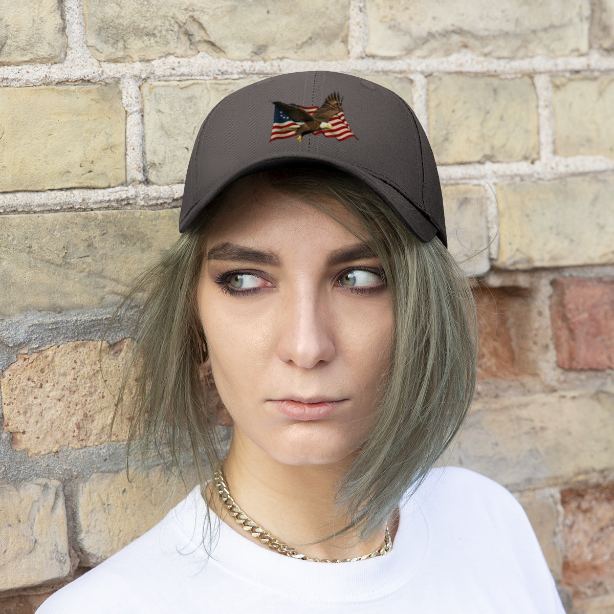 Eagle On American Flag Twill Cap worn by a model with short hair against a brick wall background.