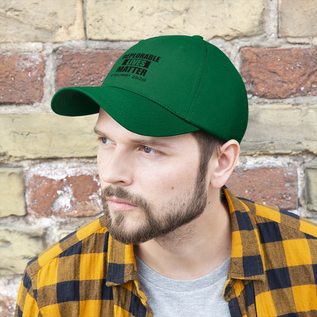 Man wearing Deplorable Lives Matter Trump 2020 Twill Cap against a brick wall, showcasing political statement.