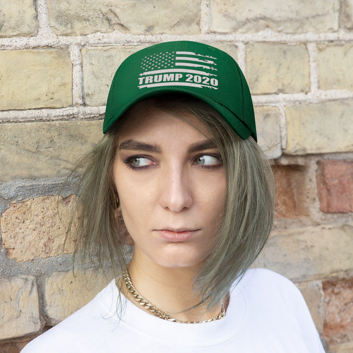 Trump 2020 Distressed American Flag Wht Ltrs Twill Cap worn by a model with short hair against a brick wall.