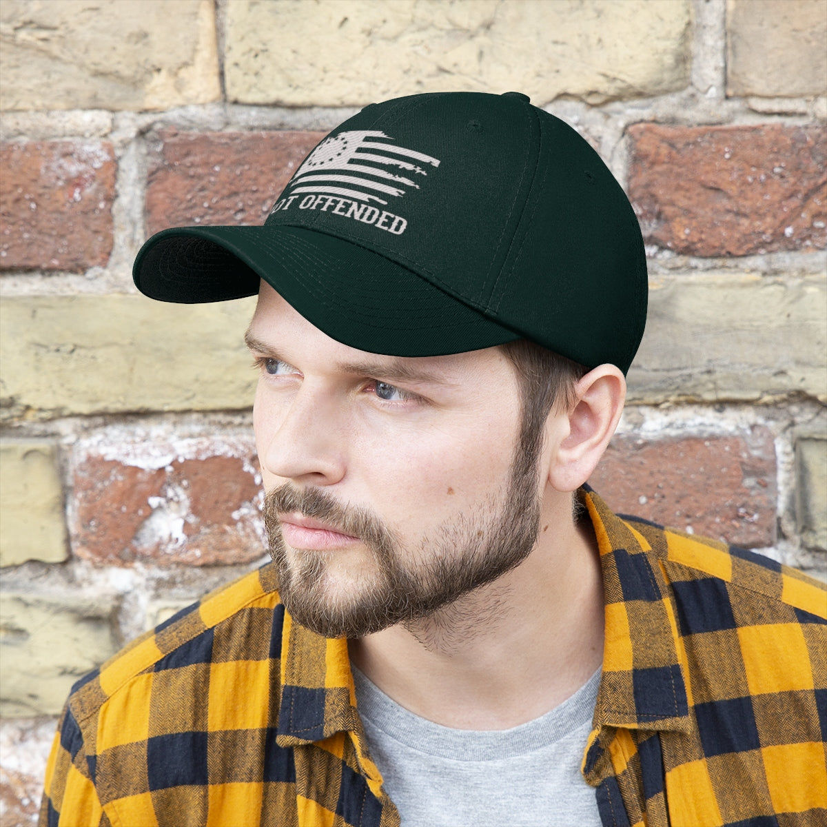 Embroidered Not Offended Adjustable Twill Cap showcased on a man against a brick wall background.