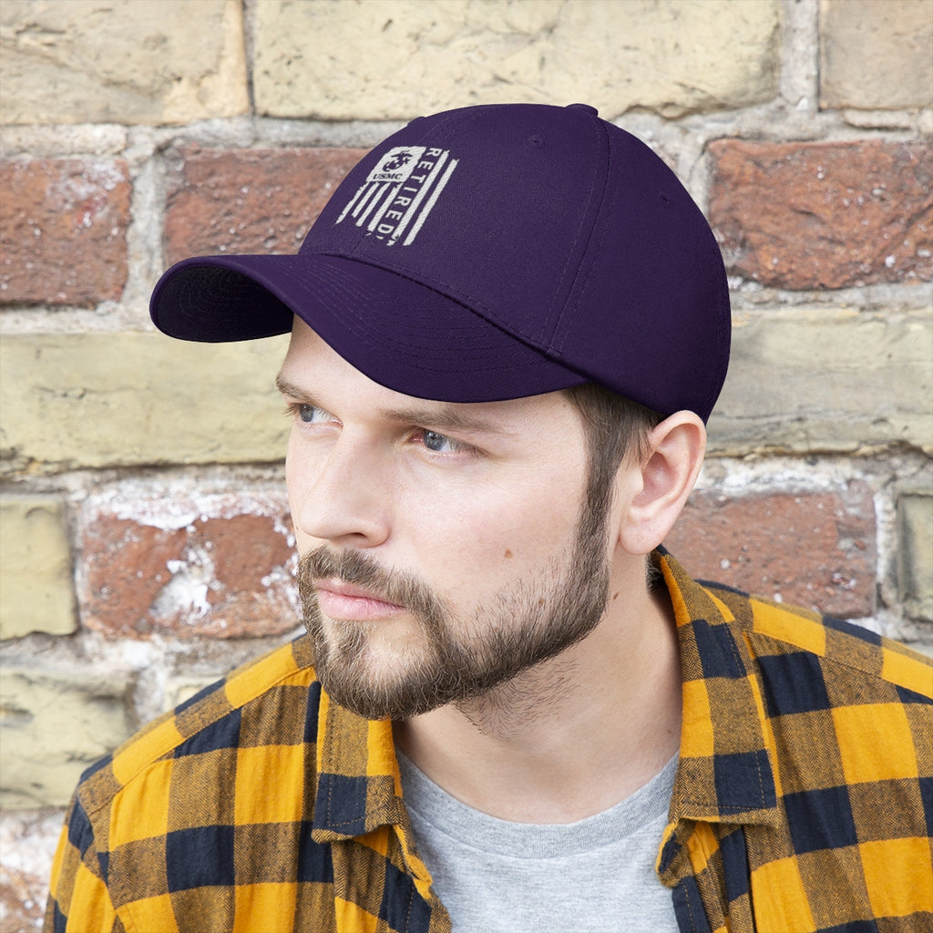 USMC Retired On Distressed American Flag Twill Cap displayed on a man wearing a plaid shirt against a textured wall.