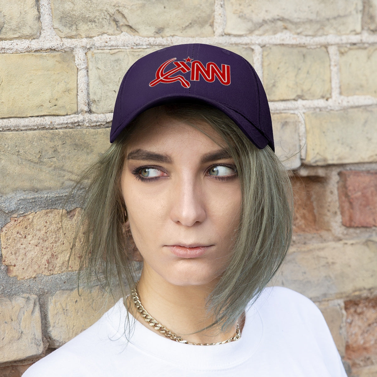 CNN Logo as Hammer and Sickle Twill Cap worn by individual against a textured wall background.