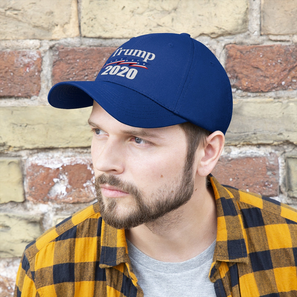 Patriotic 2020 Twill Cap for Trump worn by a man with a beard, set against a textured brick wall.