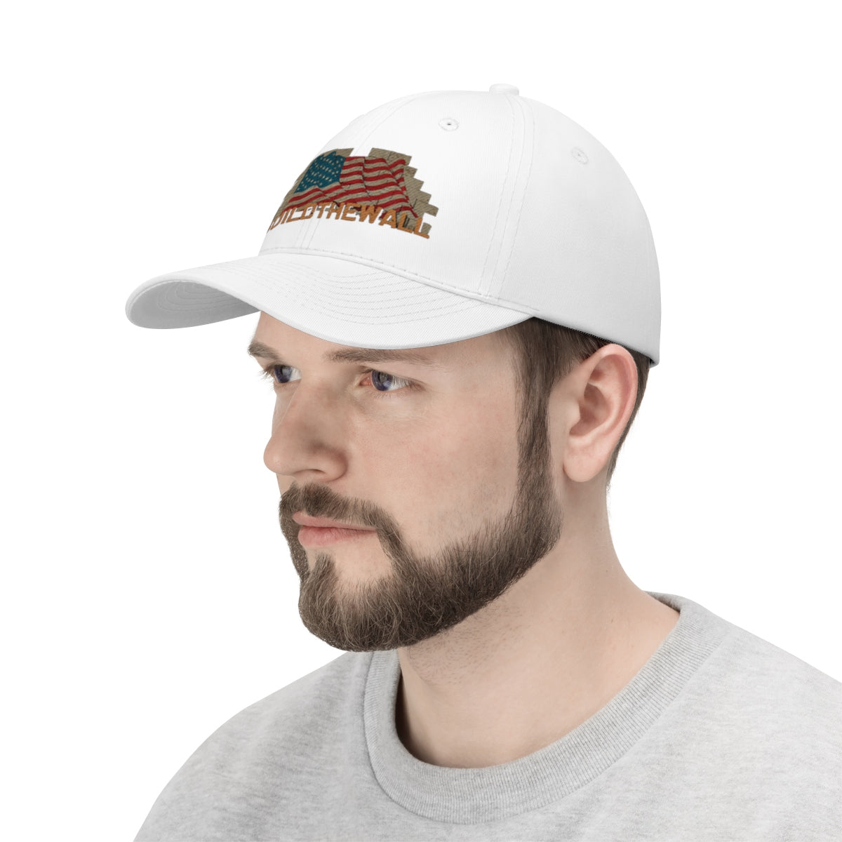 Build The Wall On American Flag Twill Cap worn by a man, showcasing a patriotic design with bold messaging.