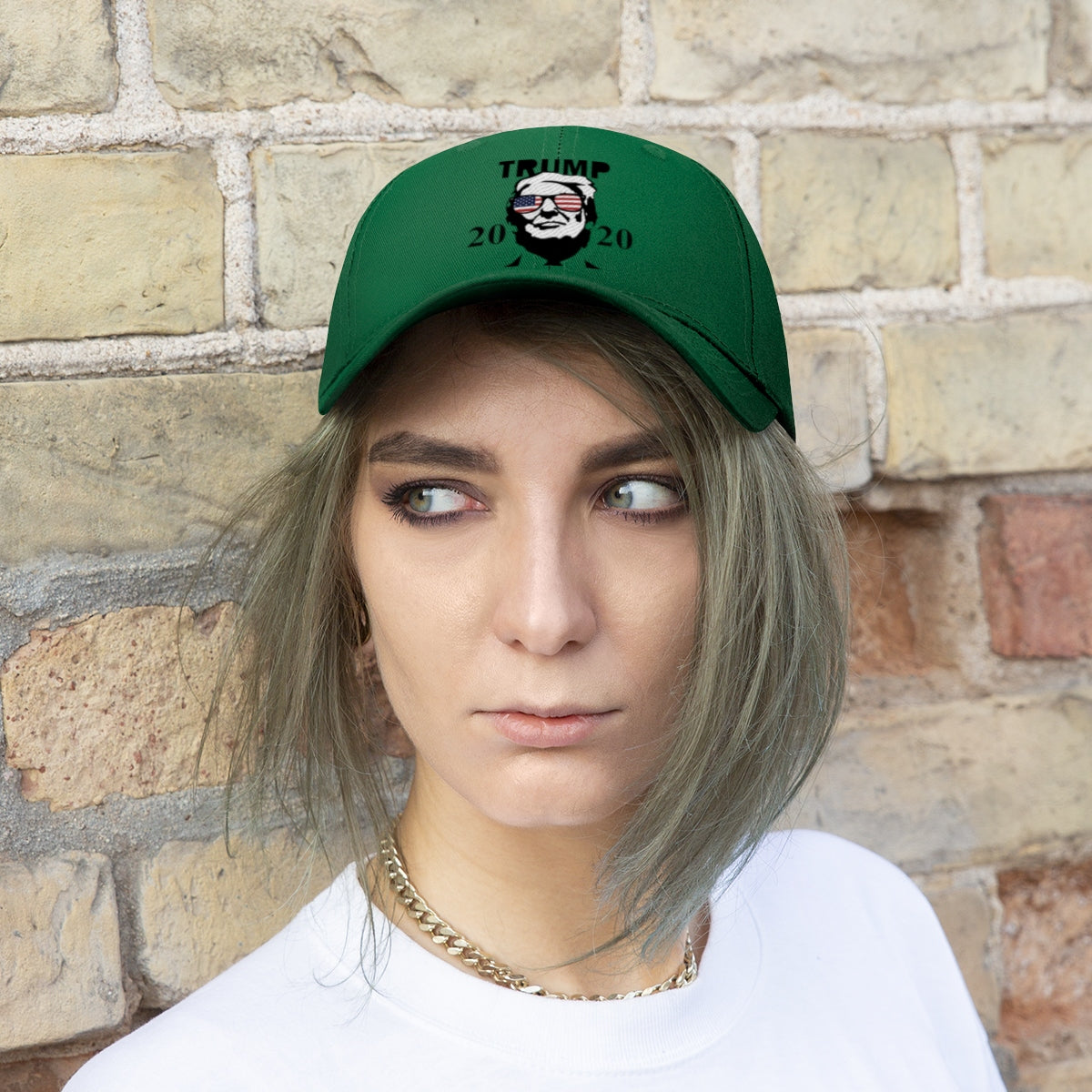 Trump 2020 With US Flag Glasses Twill Cap worn by a model against a brick wall backdrop.