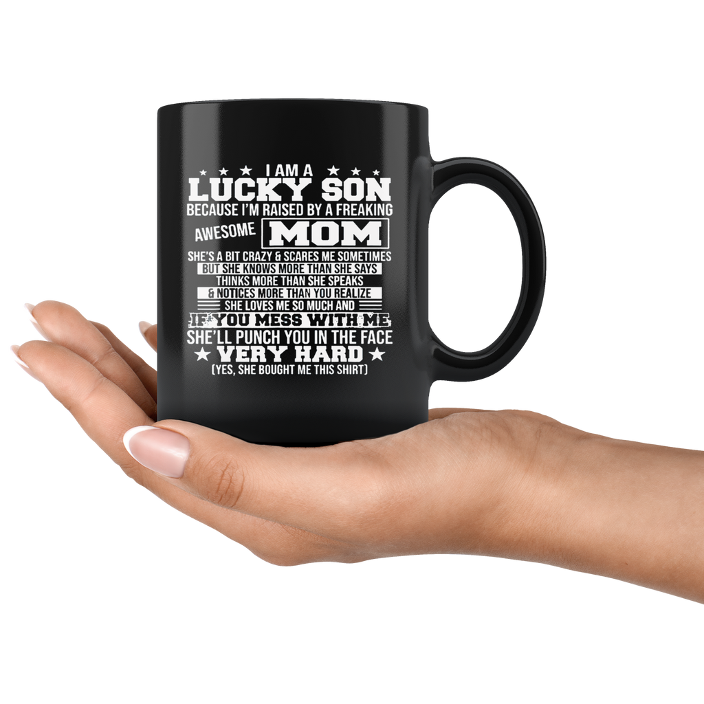 Black ceramic mug with 'Lucky Son Raised By An Awesome Mom' text, held in hand, 11oz, high gloss finish, ORCA coating